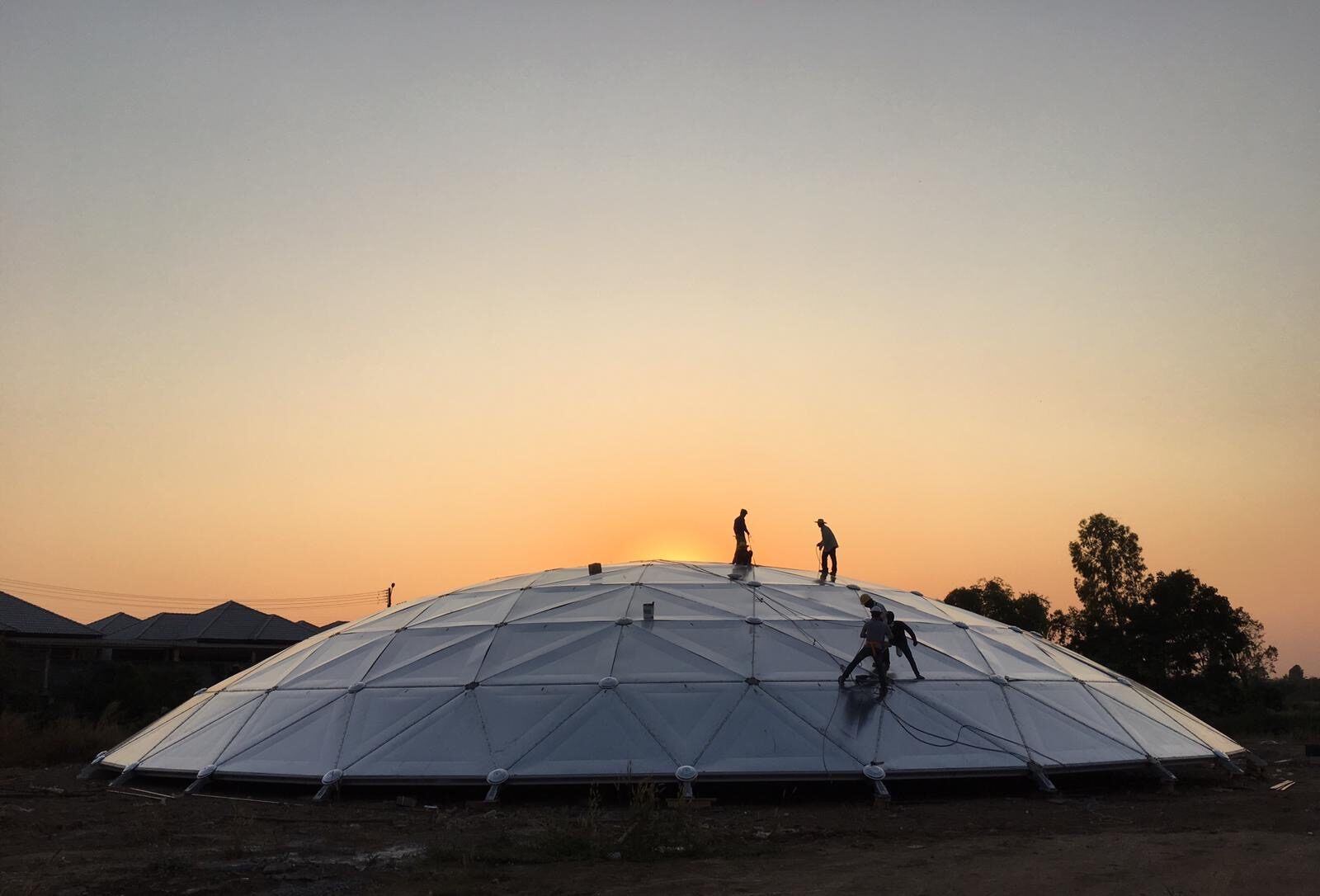 Finished aluminum geodesic dome cover installed on a steel tank in an industrial yard