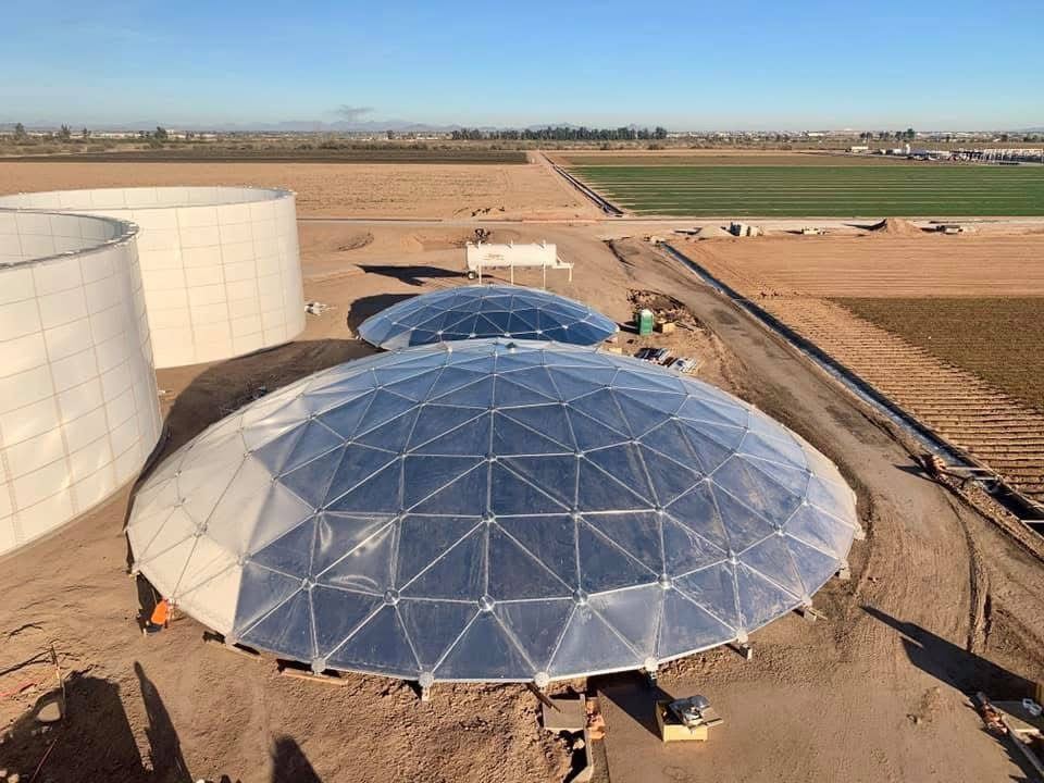 Aerial view of two clear-span aluminum geodesic domes on liquid storage tanks