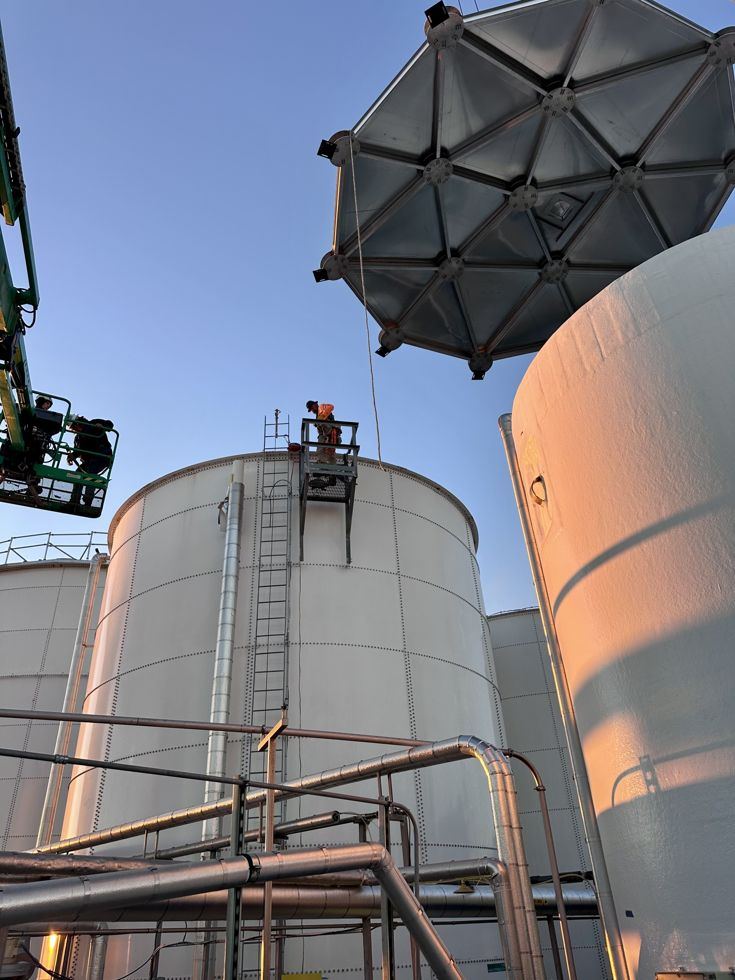 Aluminum geodesic dome being set onto an existing bolted steel tank by crane