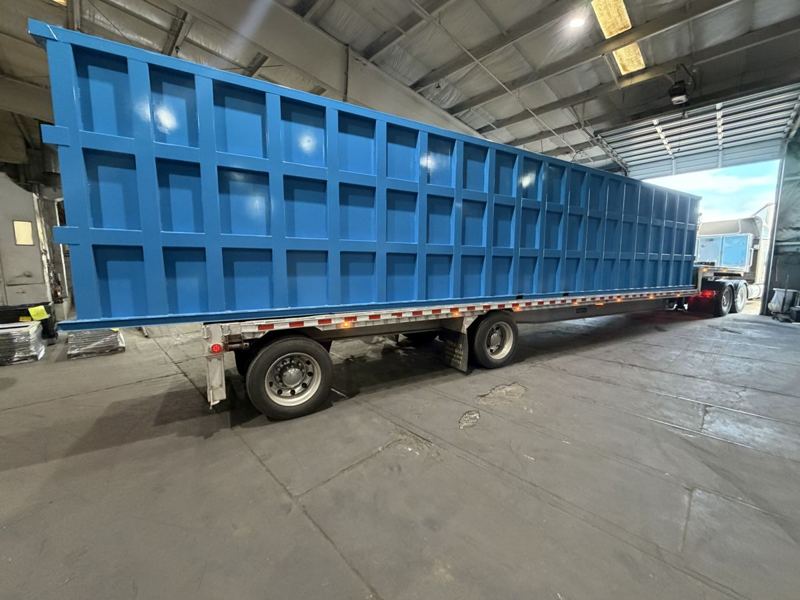 A finished EnviroBox modular steel tank loaded on a flatbed trailer