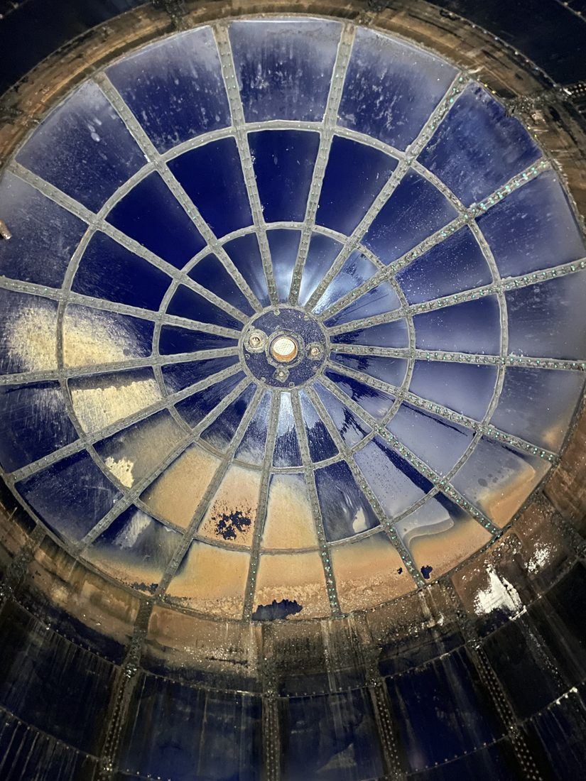 Interior roof of an aging glass-lined steel tank showing coating wear and staining