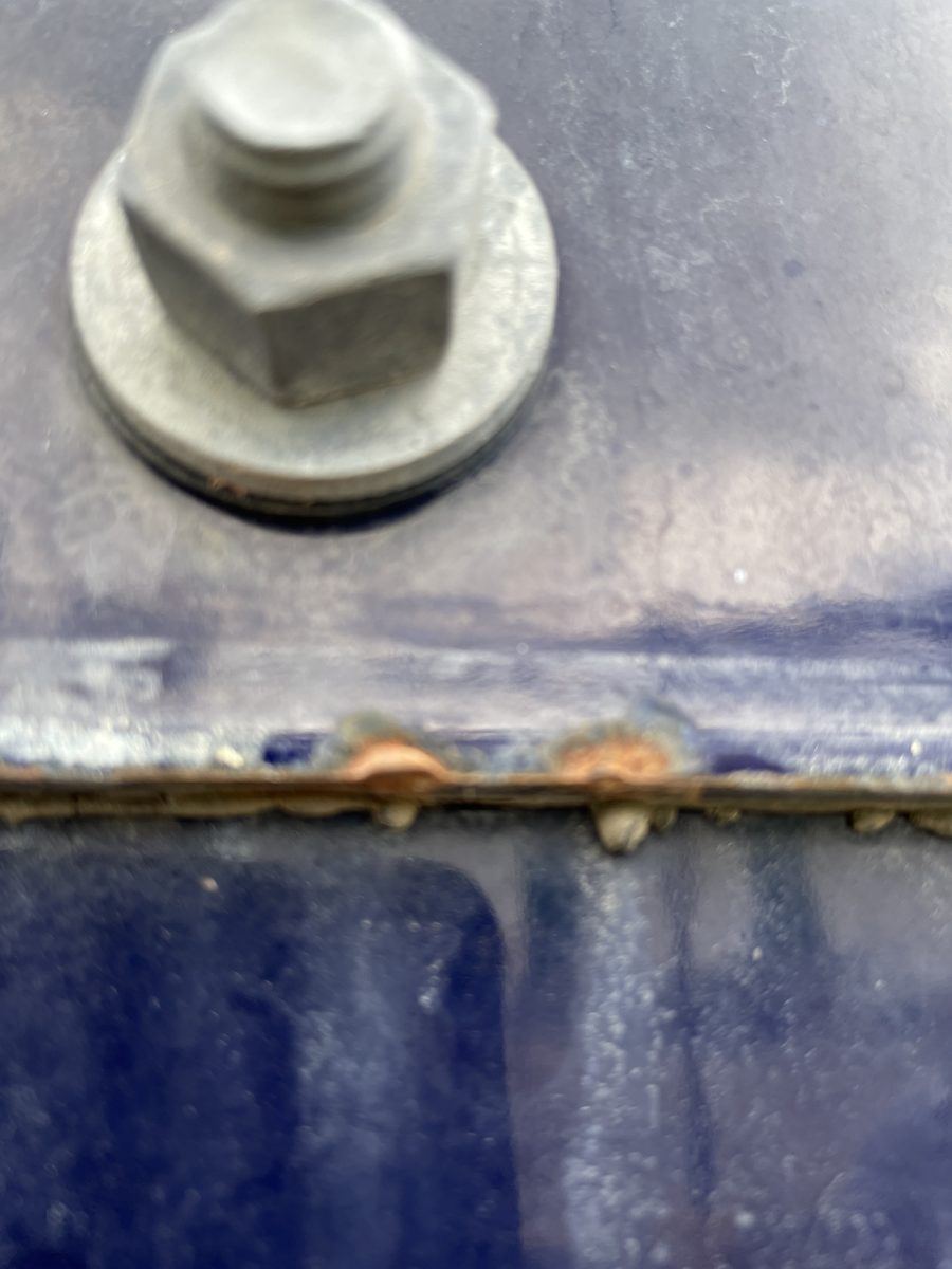 Edge-coverage failure on a glass-fused-to-steel panel with corrosion bleeding through