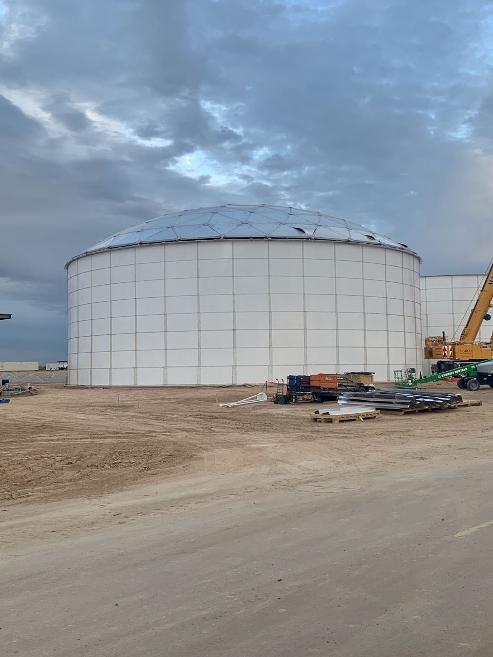 White bolted steel tank topped with an aluminum geodesic dome roof at dusk