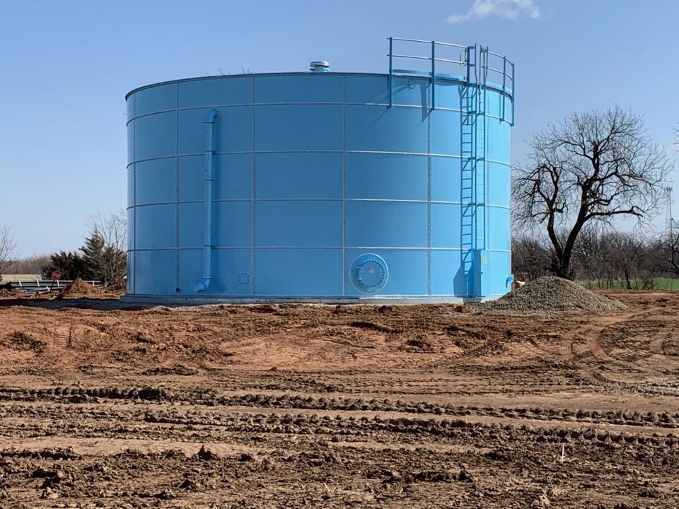 Blue bolted steel tank with dome roof on a rural site under a clear sky
