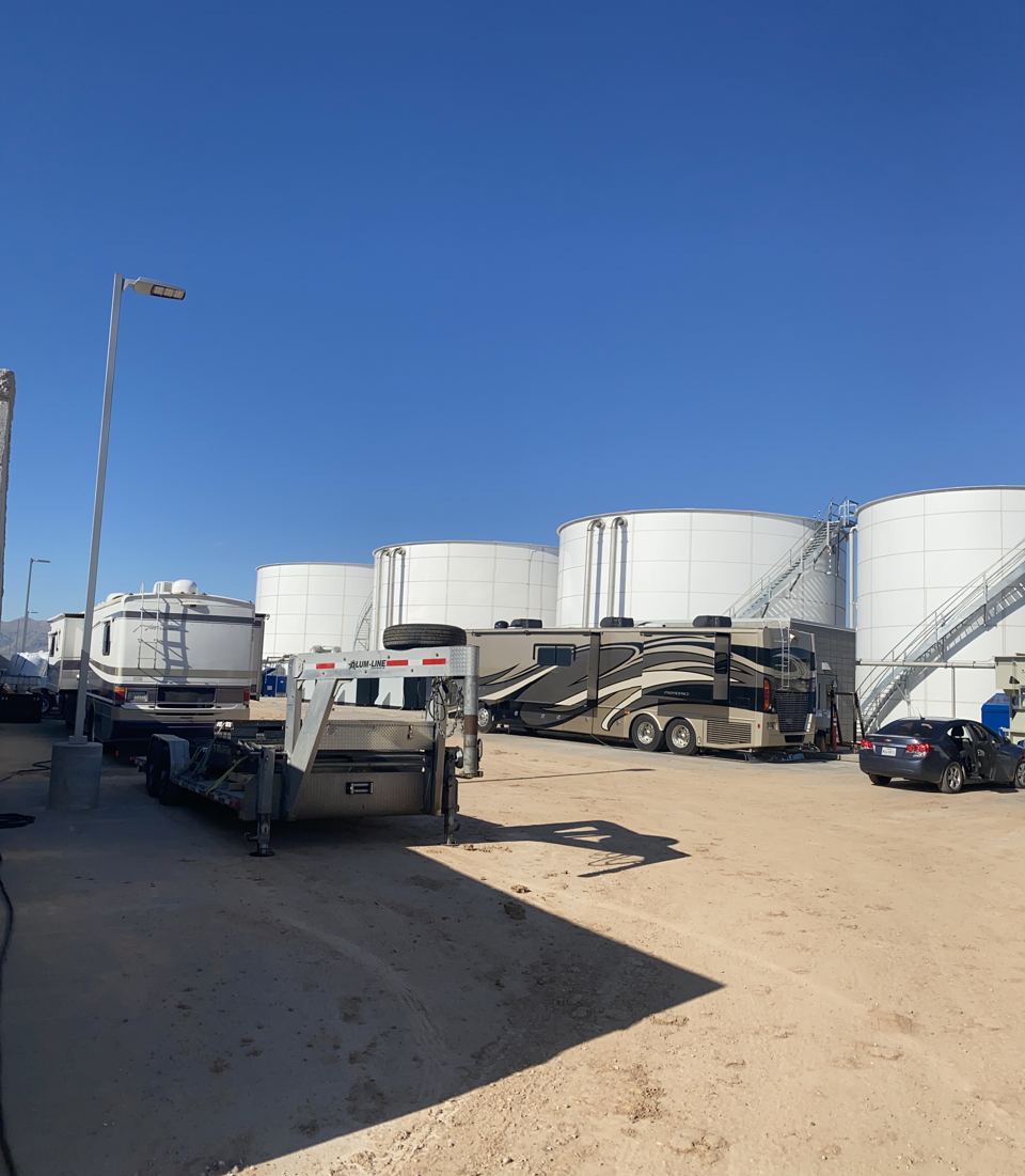Storage tank farm of multiple white bolted steel tanks under a clear desert sky