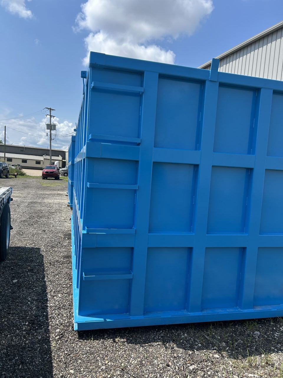 Close-up of the externally reinforced panel grid and welded bracing on the side wall of a bright blue modular steel tank in the yard