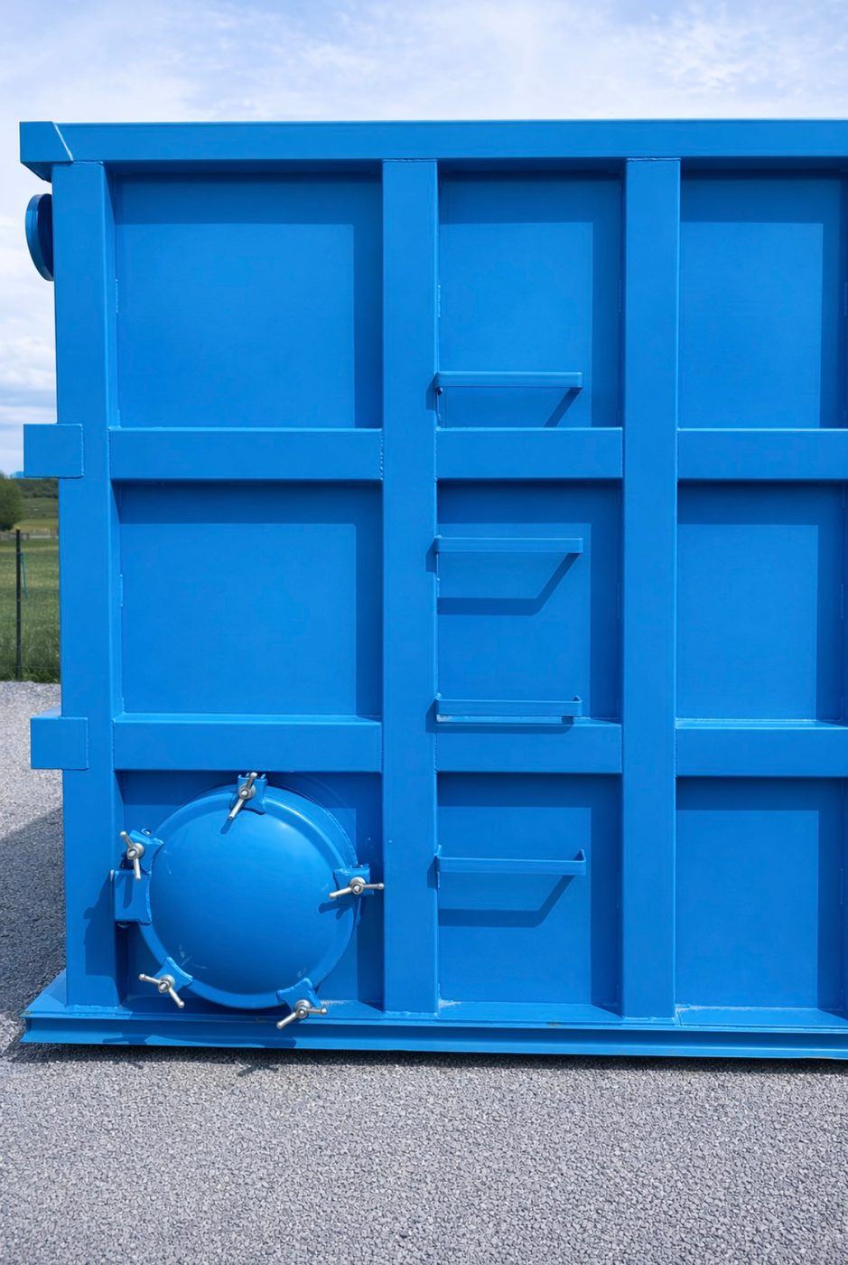 Close-up of a modular bolted steel tank end wall showing the reinforced panel grid and a bolted circular manway