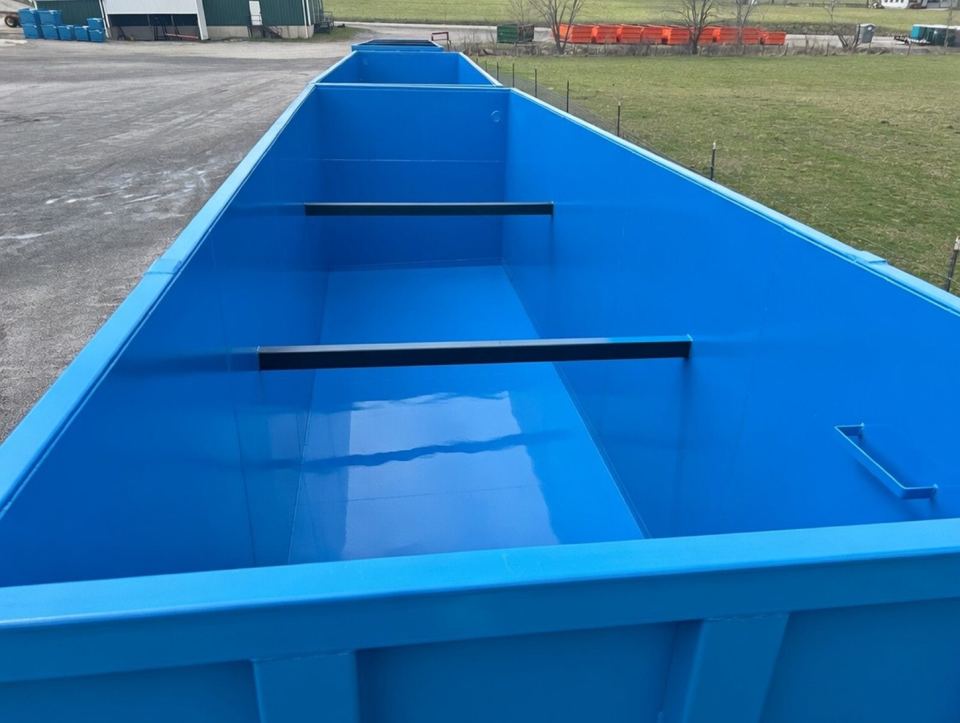 Looking down into the coated interior of an open-top blue modular steel tank with internal baffle bars, staged outdoors
