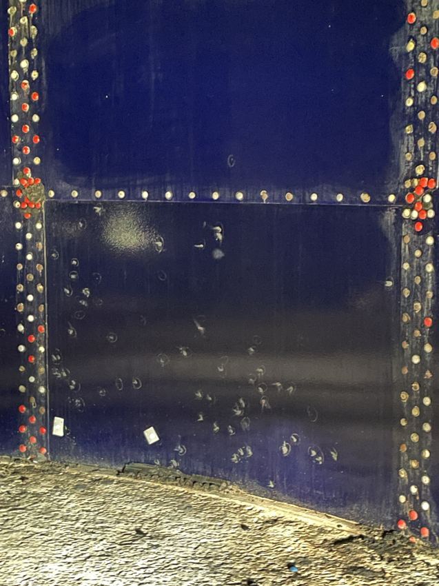 Blistered and pitted glass-fused-to-steel coating near a bolted panel seam