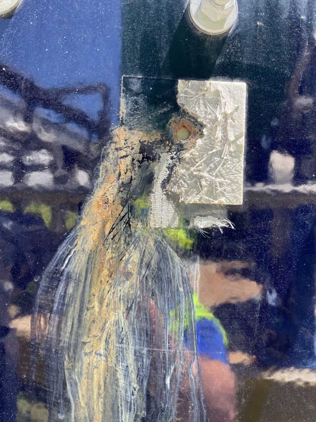 Rust breaking through a failed glass-fused-to-steel coating with a failing fiberglass patch