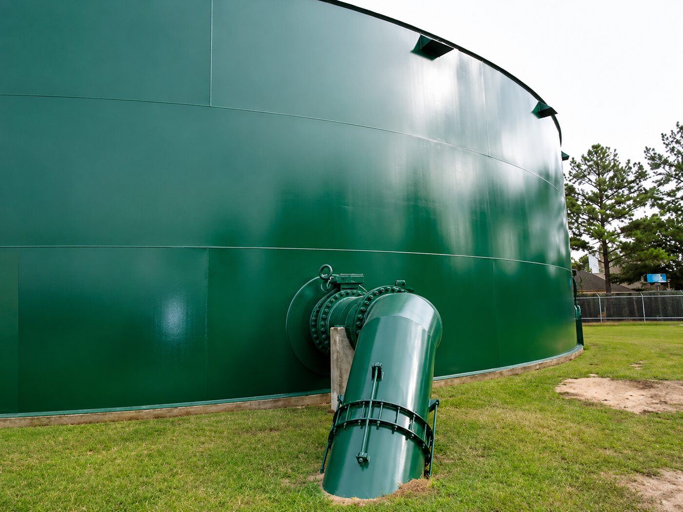 Green exterior protective coating on a large steel tank with a bolted nozzle and piping penetration