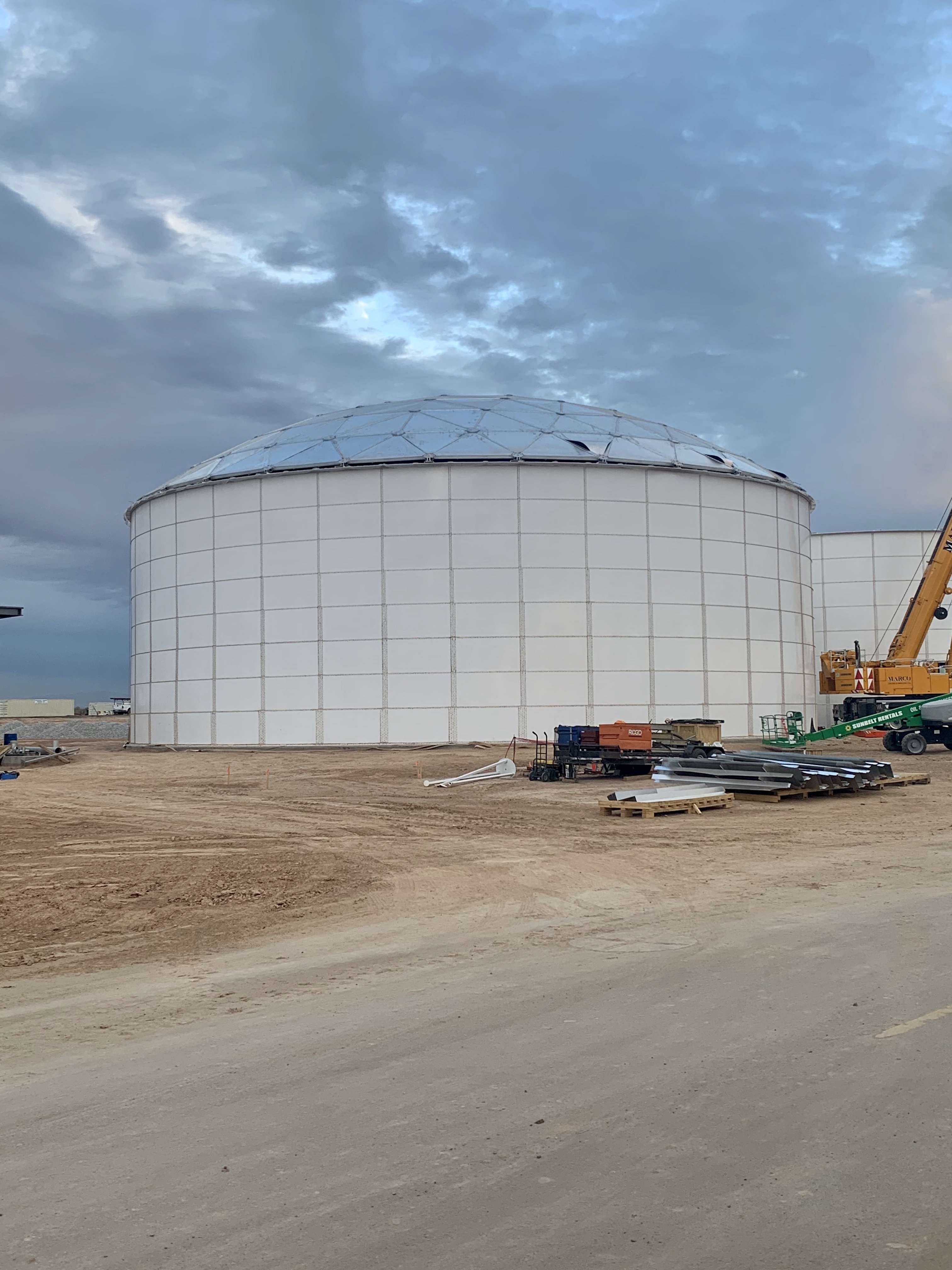 White bolted steel tank topped with an aluminum geodesic dome roof at dusk