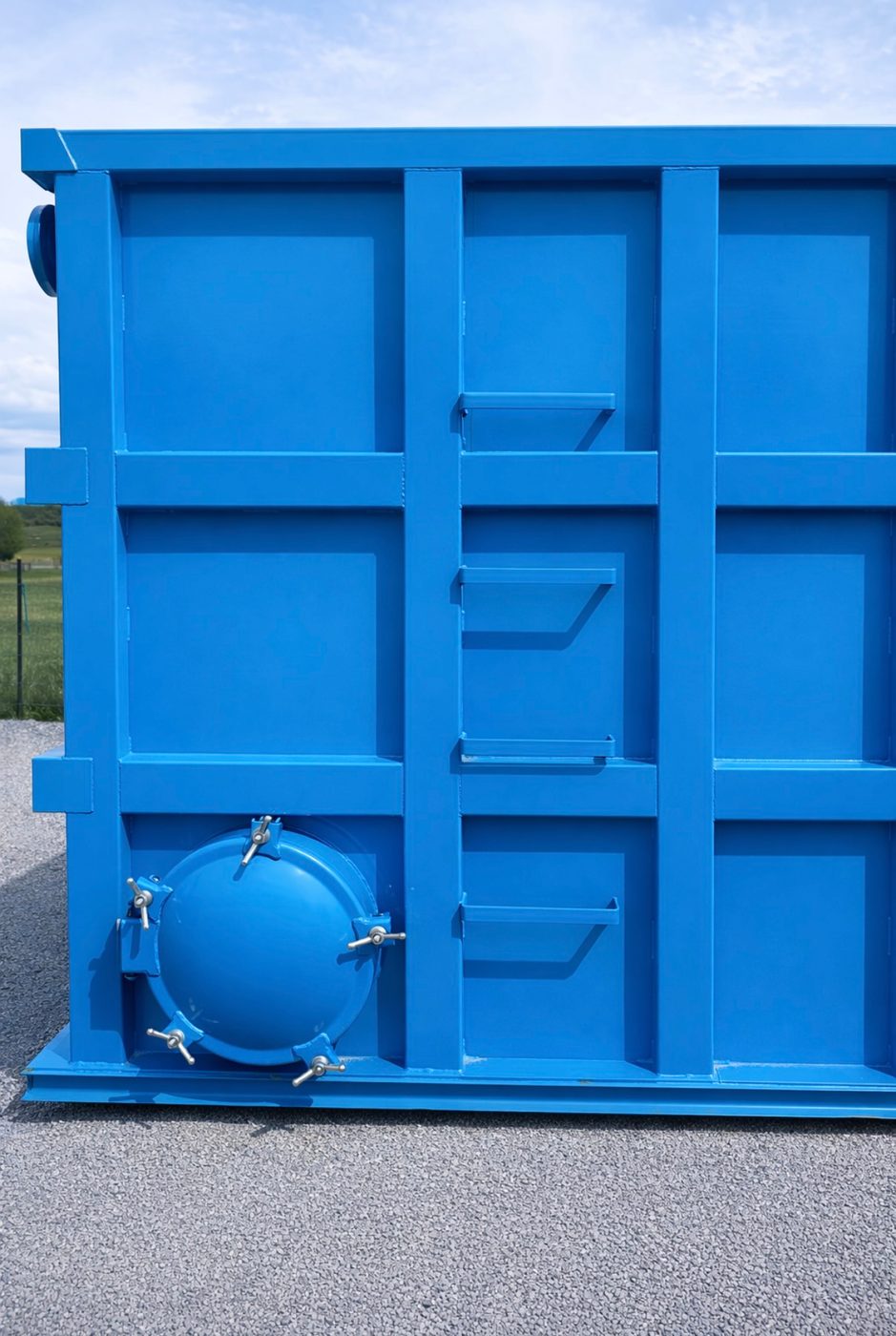 Close-up of a modular bolted steel tank end wall showing the reinforced panel grid and a bolted circular manway